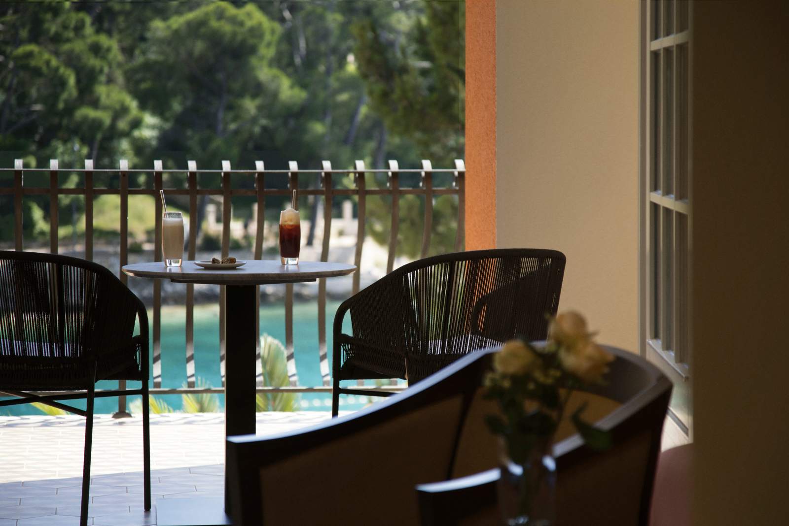 A tranquil balcony setup with a view of the pool, showcasing comfortable chairs and a table with refreshing beverages, perfect for a leisurely afternoon