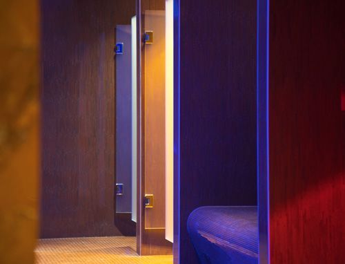 Modern spa interior featuring a curved bench with vibrant blue lighting and adjacent wooden doors