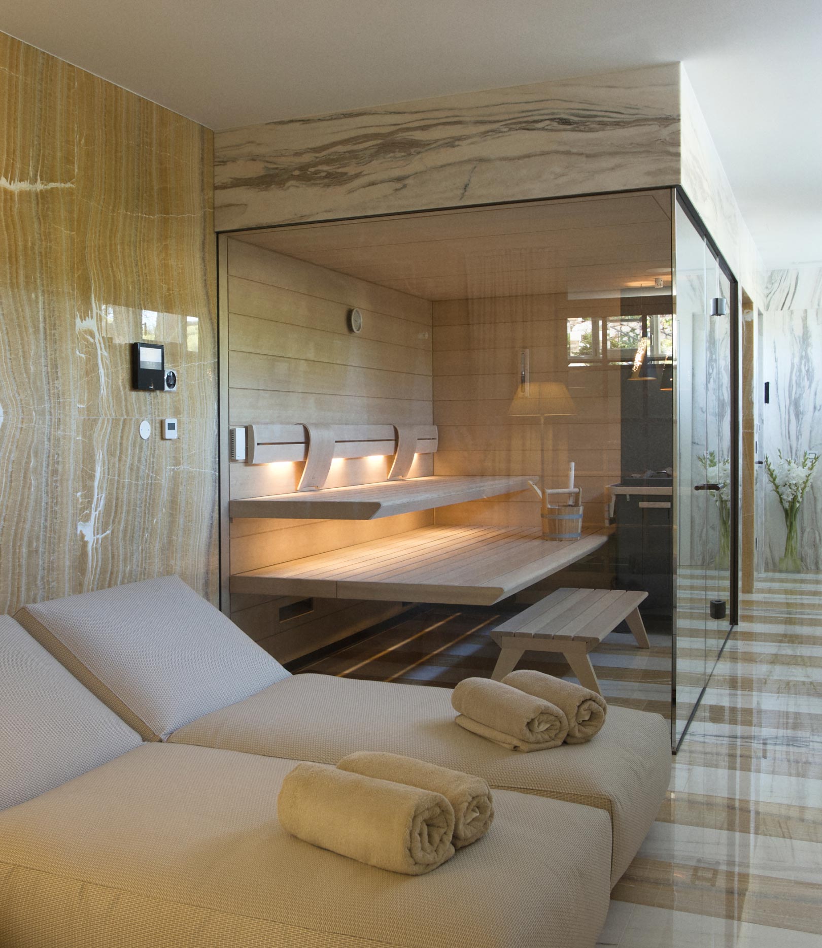 A serene spa setting with a modern wooden sauna, relaxing loungers, and marble accents that create a luxurious and restful retreat