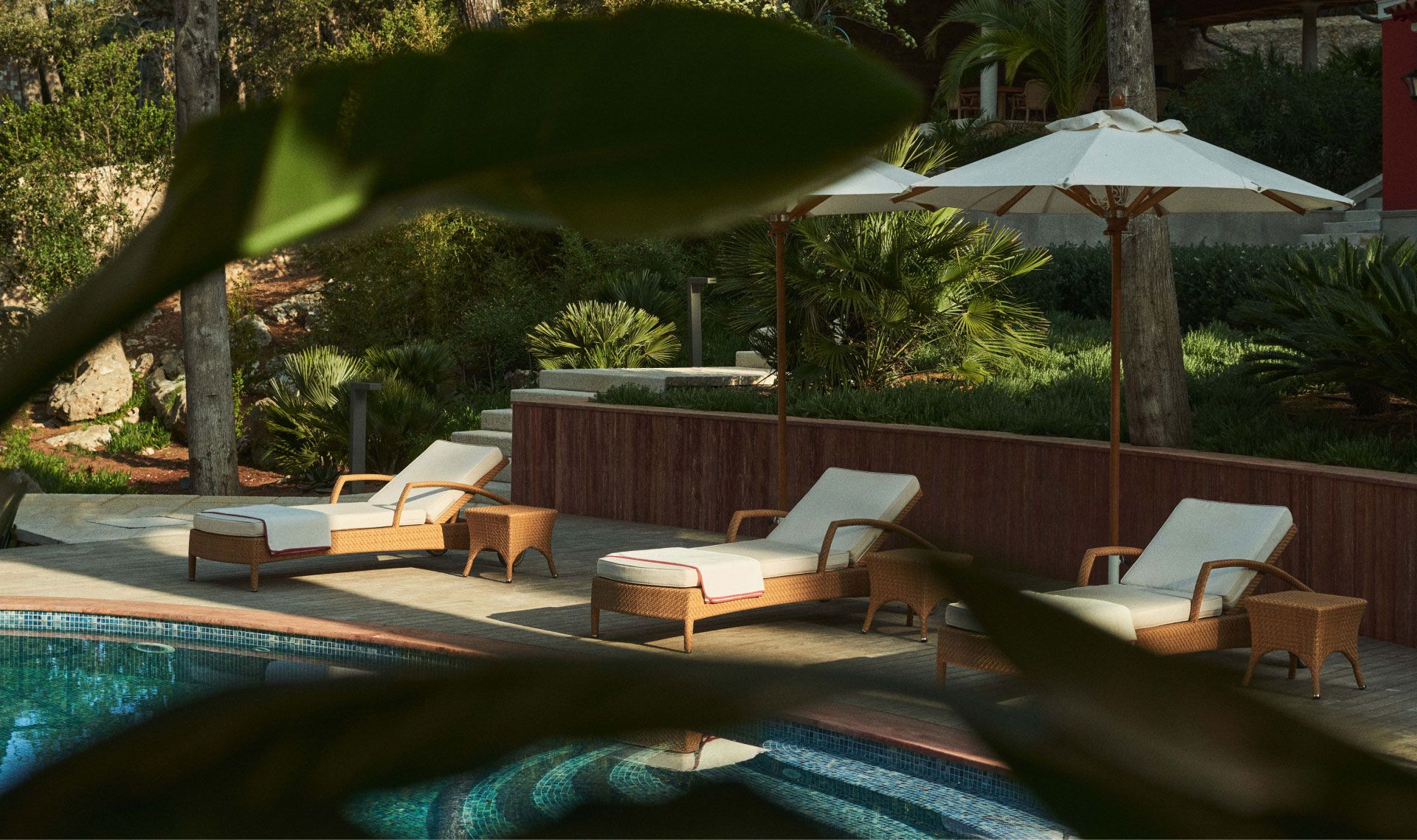 Poolside loungers under umbrellas surrounded by lush greenery, offering a tranquil spot for relaxation